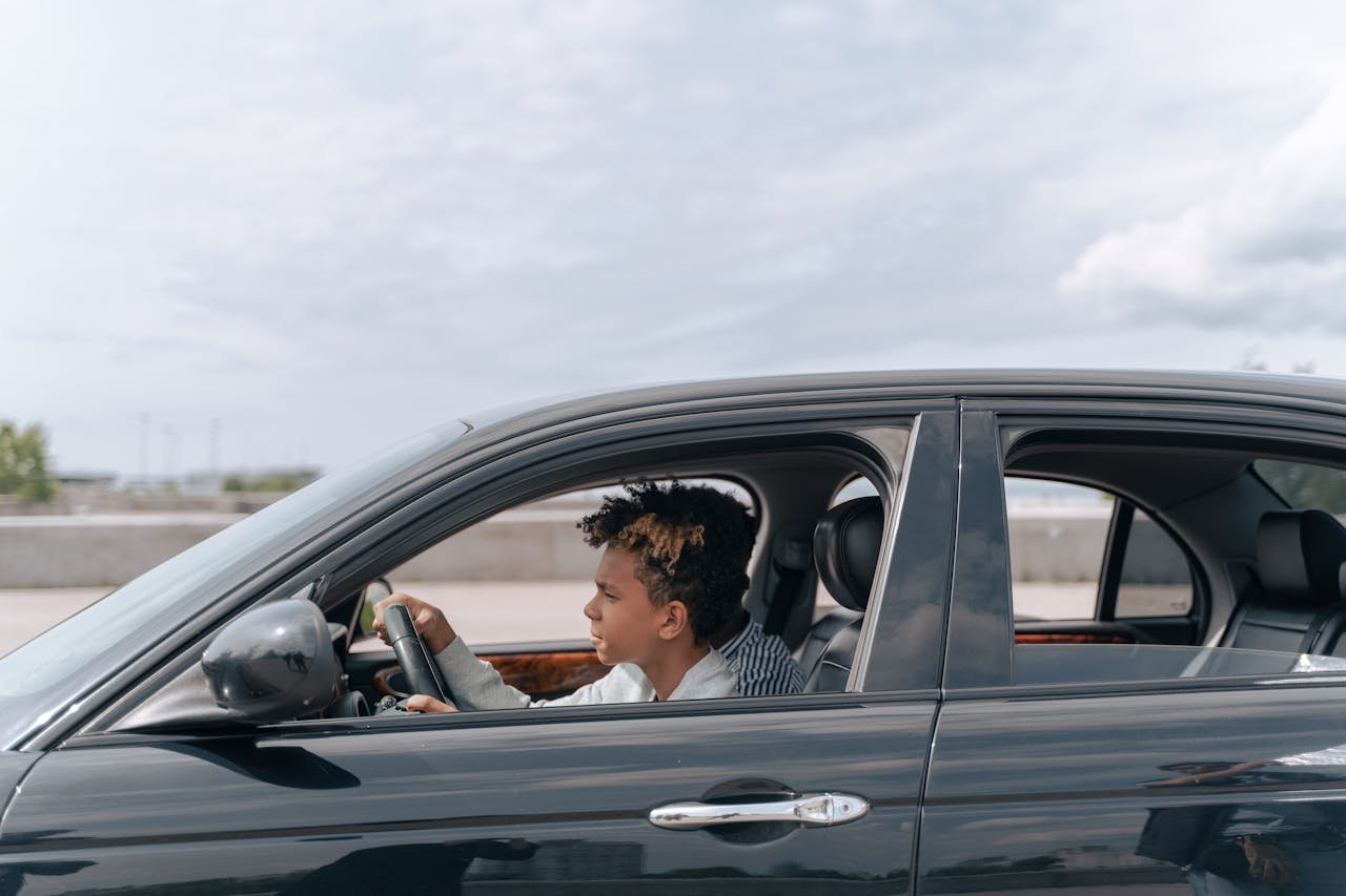 Crafting Captivating Headlines: Your awesome post title goes here Side view of a young male teenager focused on driving a car in bright daylight.